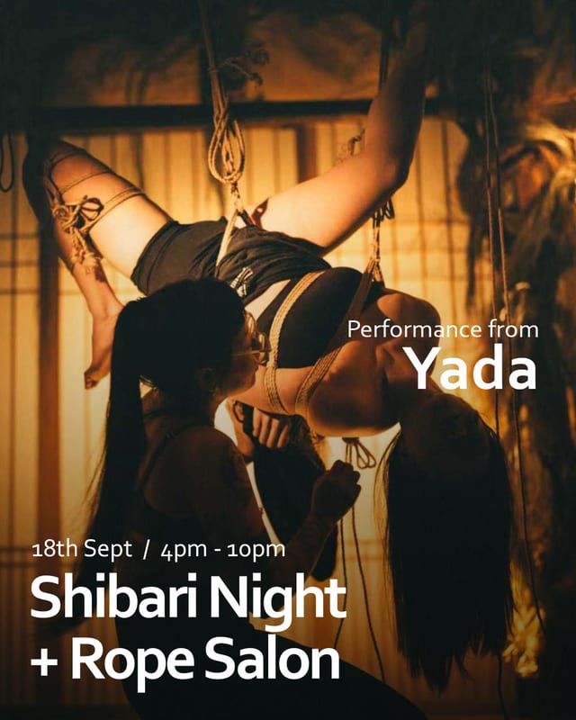 Yada suspended in rope, lit by warm lantern light in a tatami room.